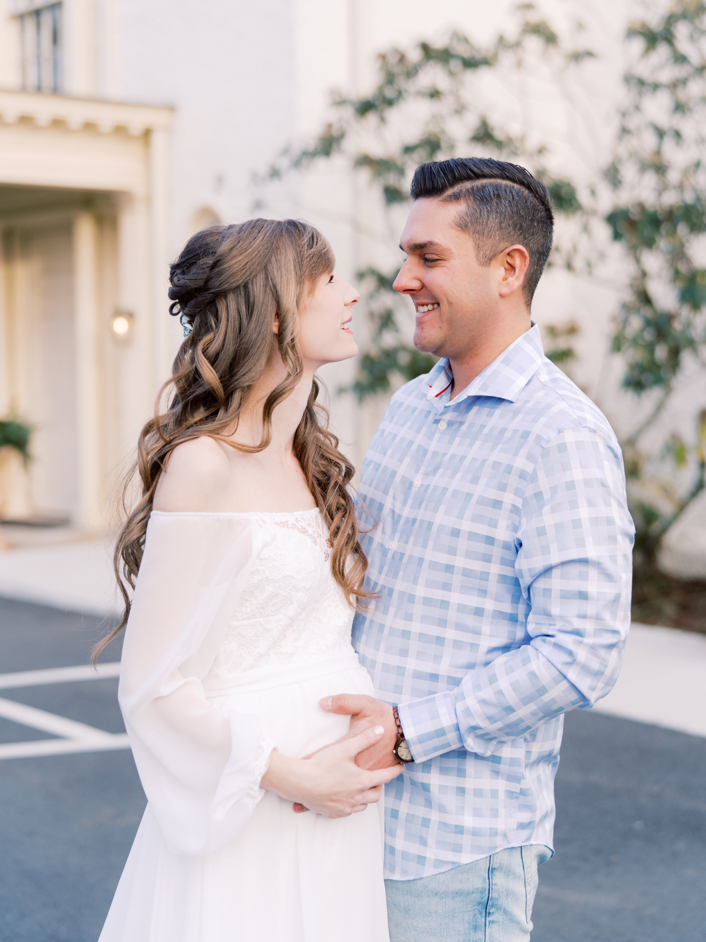 Couple smiling at each other in front of Rust Manor House in Leesburg Virginia for their maternity session