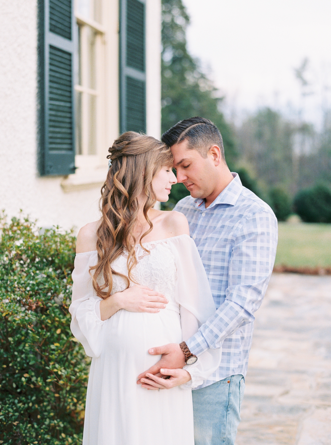 Couple resting foreheads on the side of Rust Manor House in Leesburg Virginia for their maternity session