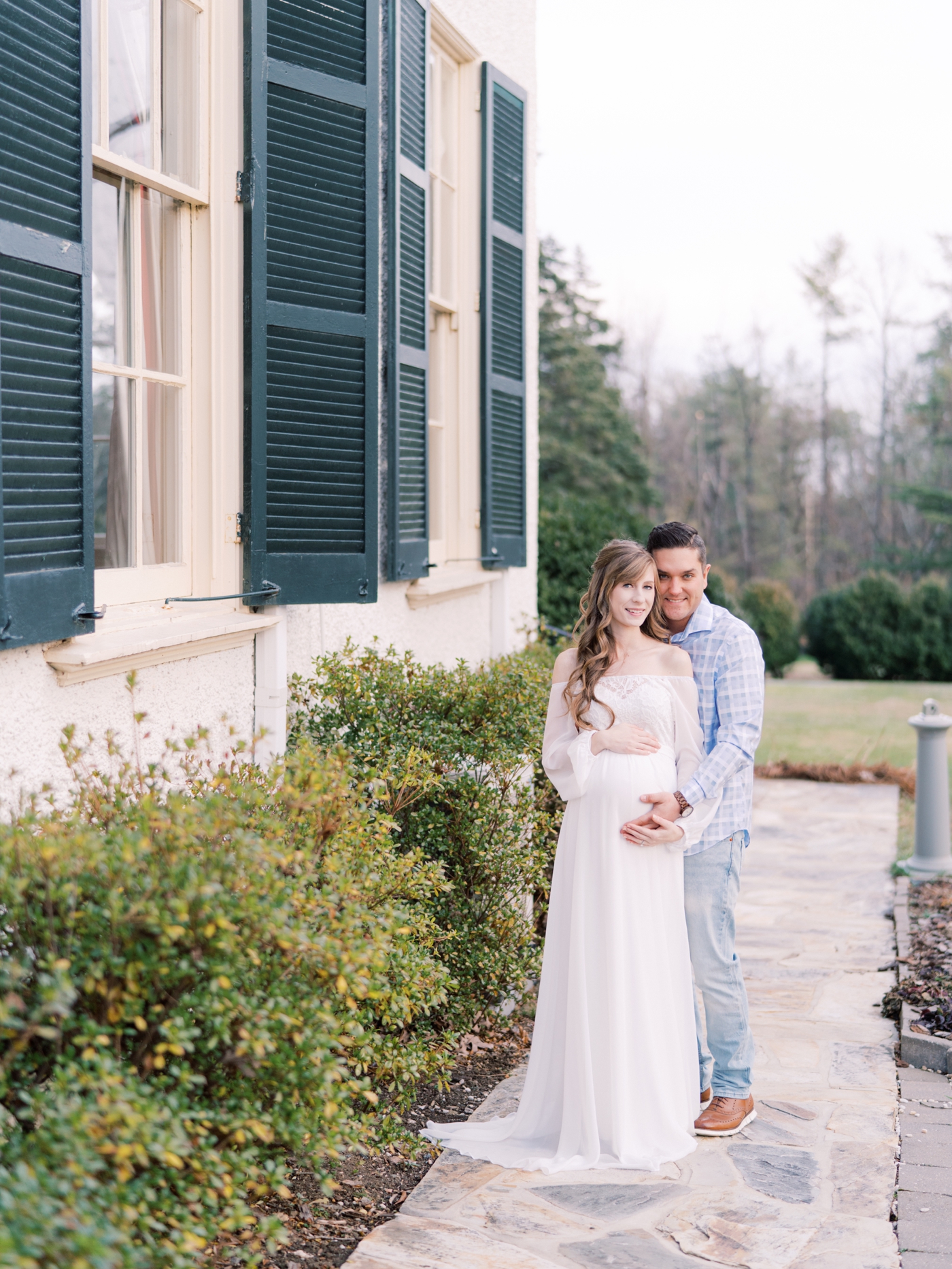 Couple smiling at the camera at Rust Manor House in Leesburg Virginia for their maternity session