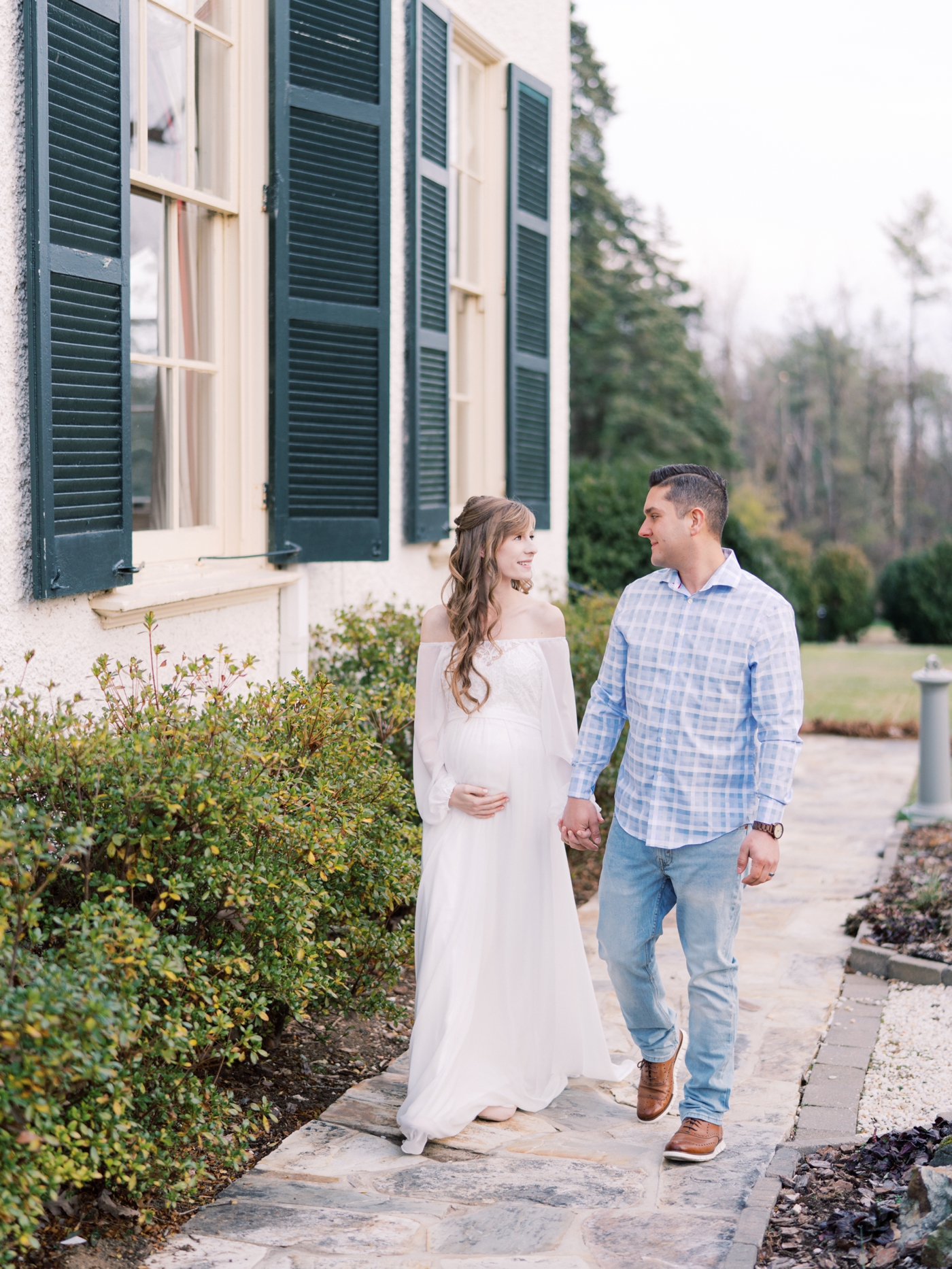 Couple walking holding hands at Rust Manor House in Leesburg Virginia for their maternity session