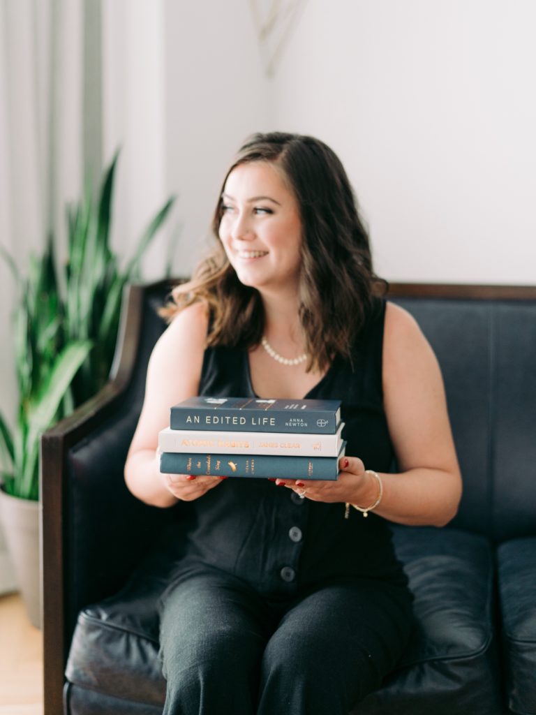 Lauren holding a stack of books during her branding session with Klaire Dixius Photography