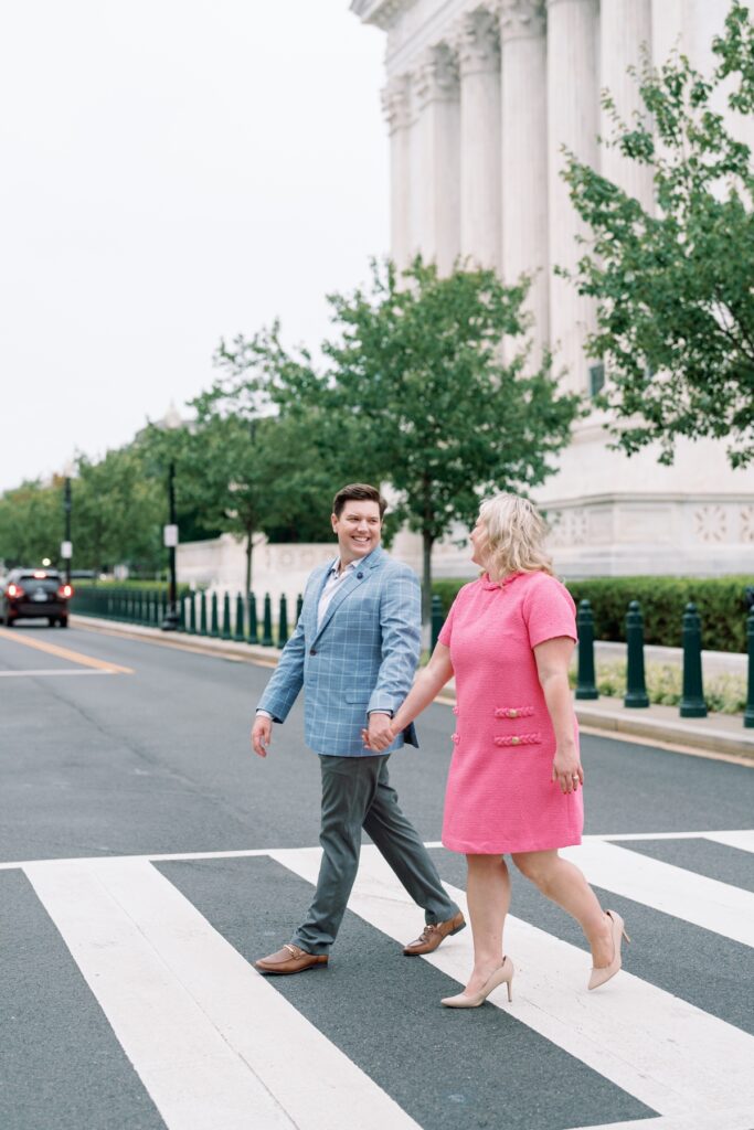 engaged Couple smiling at the camera walking across a crosswalk in washington dc